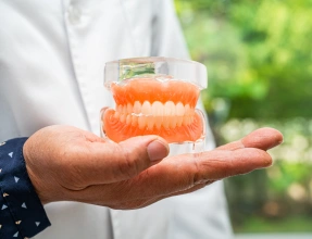 Dental professional holding a full denture to demonstrate a complete tooth replacement solution at South Arlington Smiles in Arlington, TX.