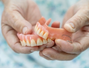 Hands holding a partial denture designed to replace missing teeth at South Arlington Smiles in Arlington, TX.