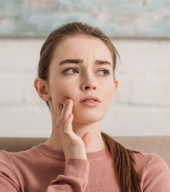 A lady experiencing a dental emergency and jaw pain, highlighting an emergency dental exam special.
