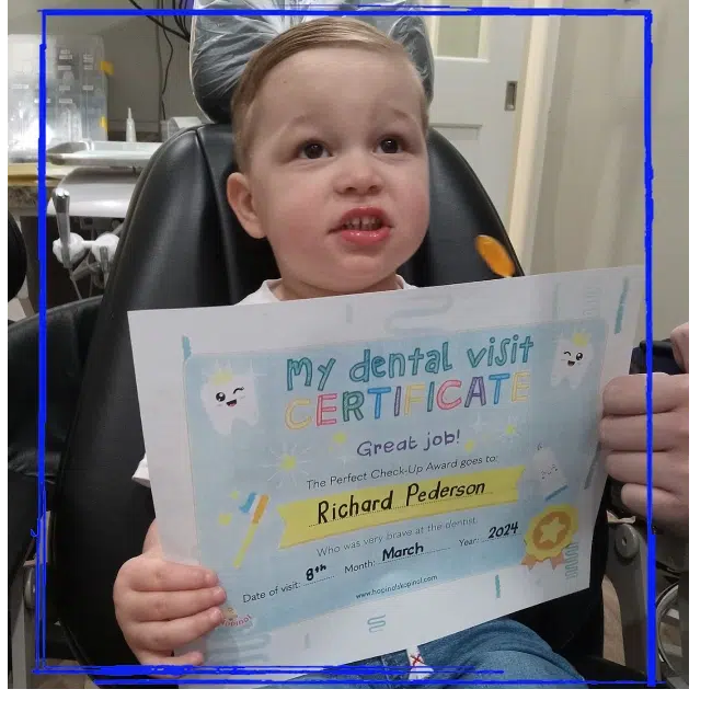 Young patient proudly holding a dental visit certificate at Spanaway Children's Dentistry near Eatonville