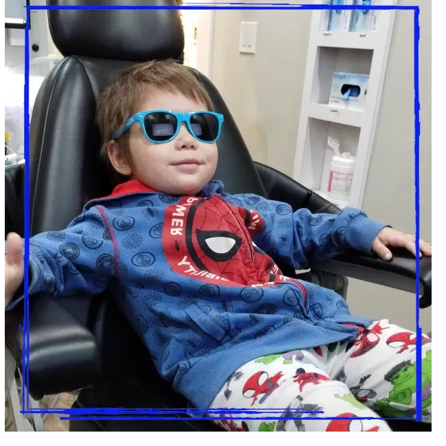 Child wearing blue sunglasses and relaxing in the dental chair at Spanaway Children's Dentistry near Graham