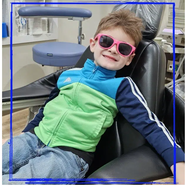 Child wearing pink sunglasses and relaxing in the dental chair at Spanaway Children's Dentistry near Graham