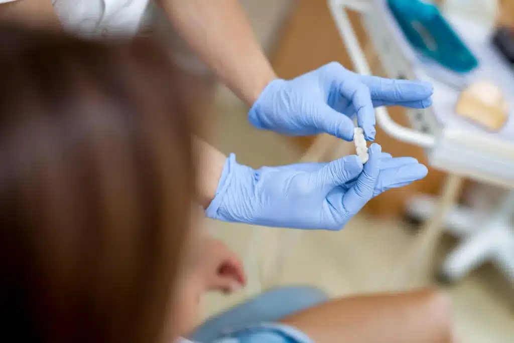 Dentist in Auburn holding a dental crown and showing it to a patient