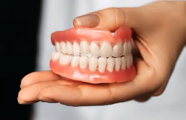 Dentist holding full denture model showing upper and lower teeth