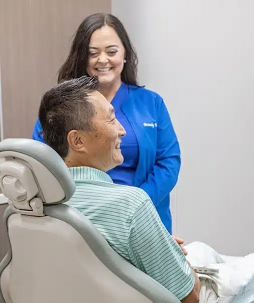 Dental team member in blue scrubs smiling with male patient in treatment chair at Thrive Family Dentistry in Auburn AL