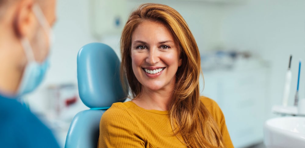Happy female dental patient smiling in treatment chair