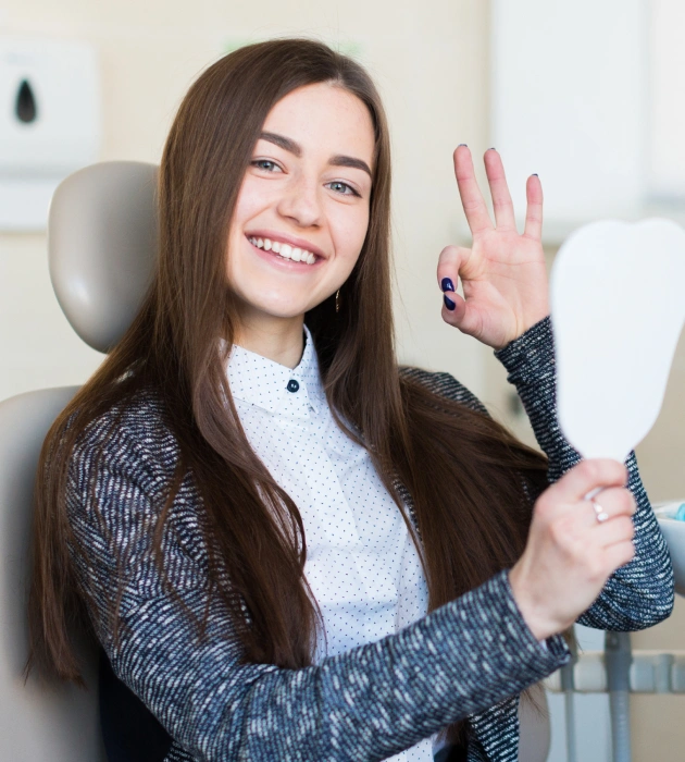 Smiling young woman waving in a dental chair during her first new patient visit