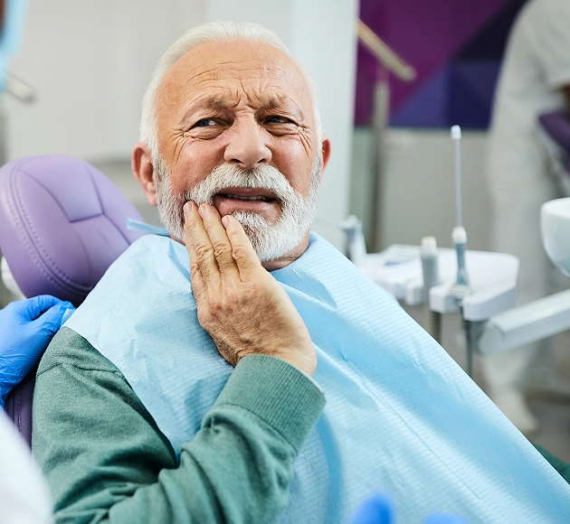 Senior patient experiencing tooth pain in a dental chair prior to an extraction consultation