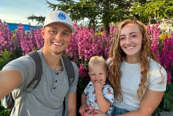 Dr. Curtis Calder, D.D.S., with his family outdoors, his wife holding their child on her lap as they stand together in a countryside garden