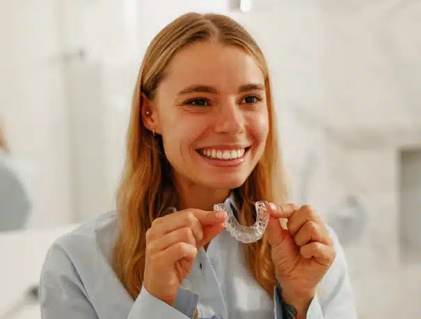 A smiling Woman holding a clear aligner during a consultation at Willow Street Dental in Chippewa Falls, WI