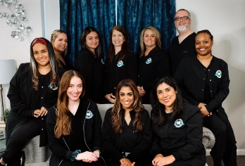 Dental practice team photo showing dentists and staff members in black uniforms at Aurora location.