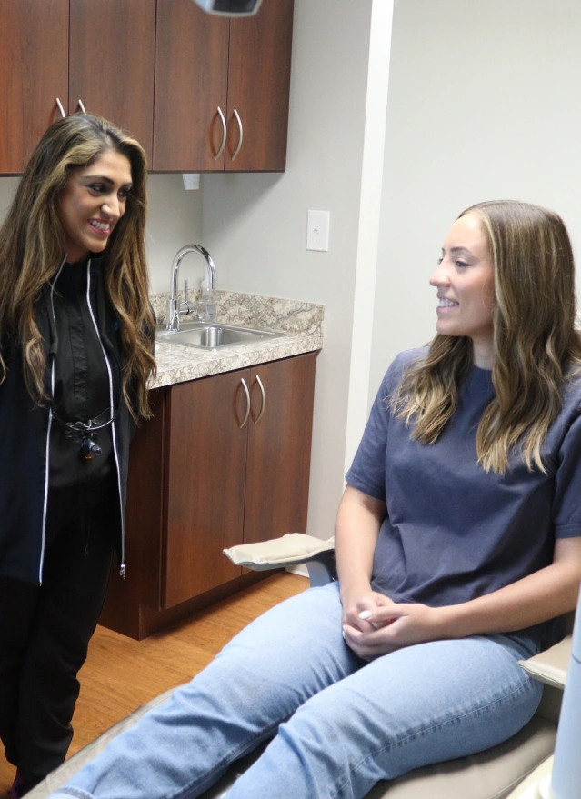 Female dental professional consulting with patient in treatment room at Aurora dental practice.