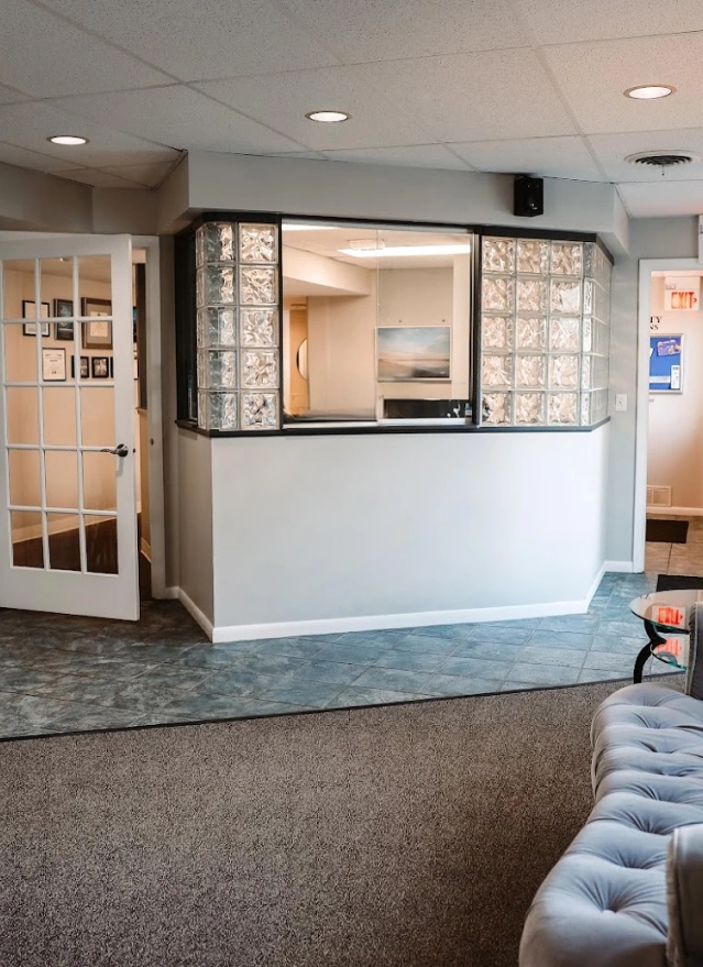 Modern dental reception area with glass block windows and white curved desk in Aurora, IL.