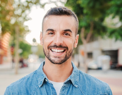 Smiling man in denim shirt at Aurora dental practice cosmetic dentistry consultation.