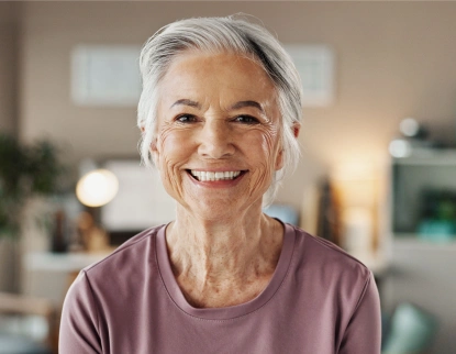 Smiling mature woman with healthy teeth in dental office setting.