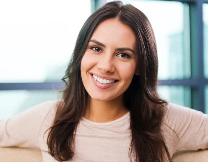 Smiling woman with bright, natural-looking teeth showcasing successful dental veneers results.