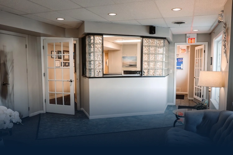 Modern dental practice reception area with white desk, glass partitions, and welcoming waiting space.