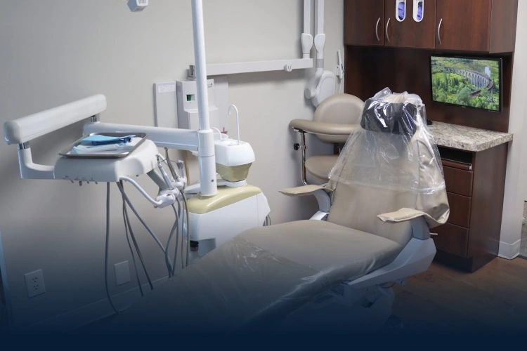 Modern dental operatory with treatment chair, overhead light, and sterilization equipment at Aurora practice.